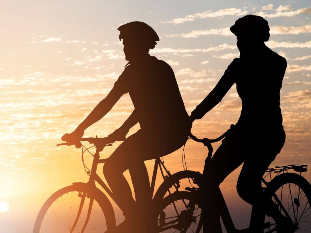 para jedzie na rowerach, w tle widoczny zachód słońca