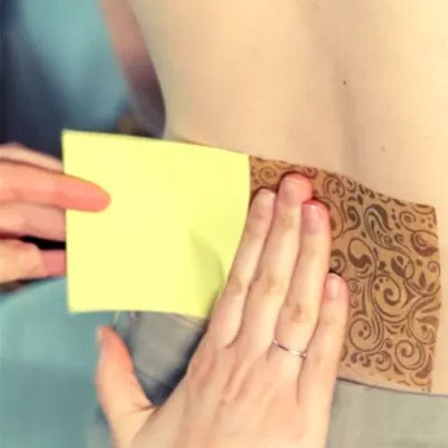 Zdjęcie ukazuje dłonie kobiece, przyklejające na dolny odcinek pleców plaster Allevi8pro